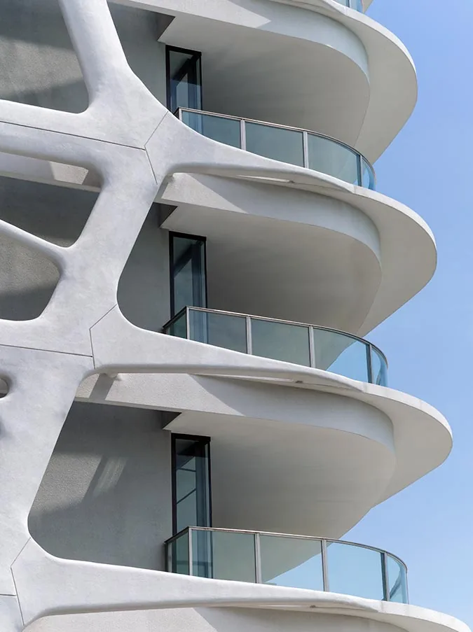 Cape Royale, photograph: a close view of the white curving balcony slabs and the branching coral-like frame of a tower against blue sky