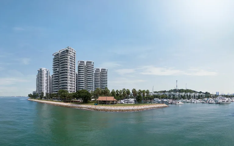 Cape Royale, photograph: the towers seen from the water, standing above the palms of the shoreline with the marina masts to the right